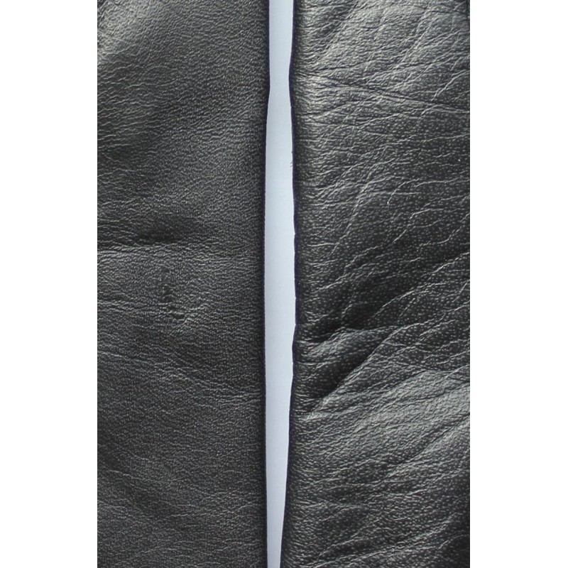 Gros plan du cuir noir de deux gants, différence de grain visible