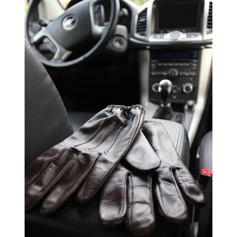 Paire de gants de conduite en cuir d’agneau marron posée sur un siège de voiture