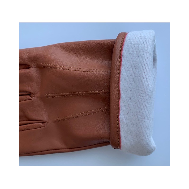 Poignet retourné d’un gant en cuir de vache marron, doublure polaire visible